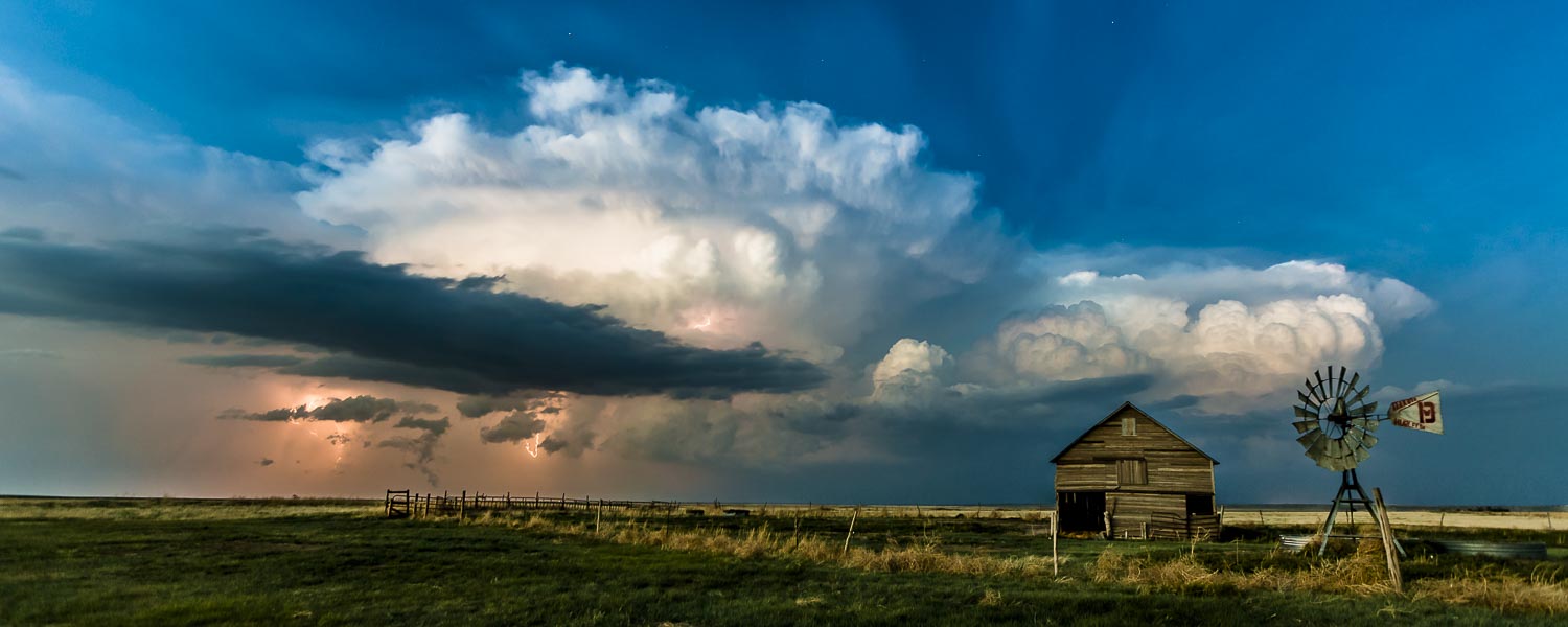 Dusk on the prairies as a lightning storm passes by an abandoned barn