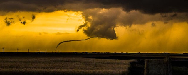 A bizarre rope of a tornado worms its way to the ground at dusk near Russell KS